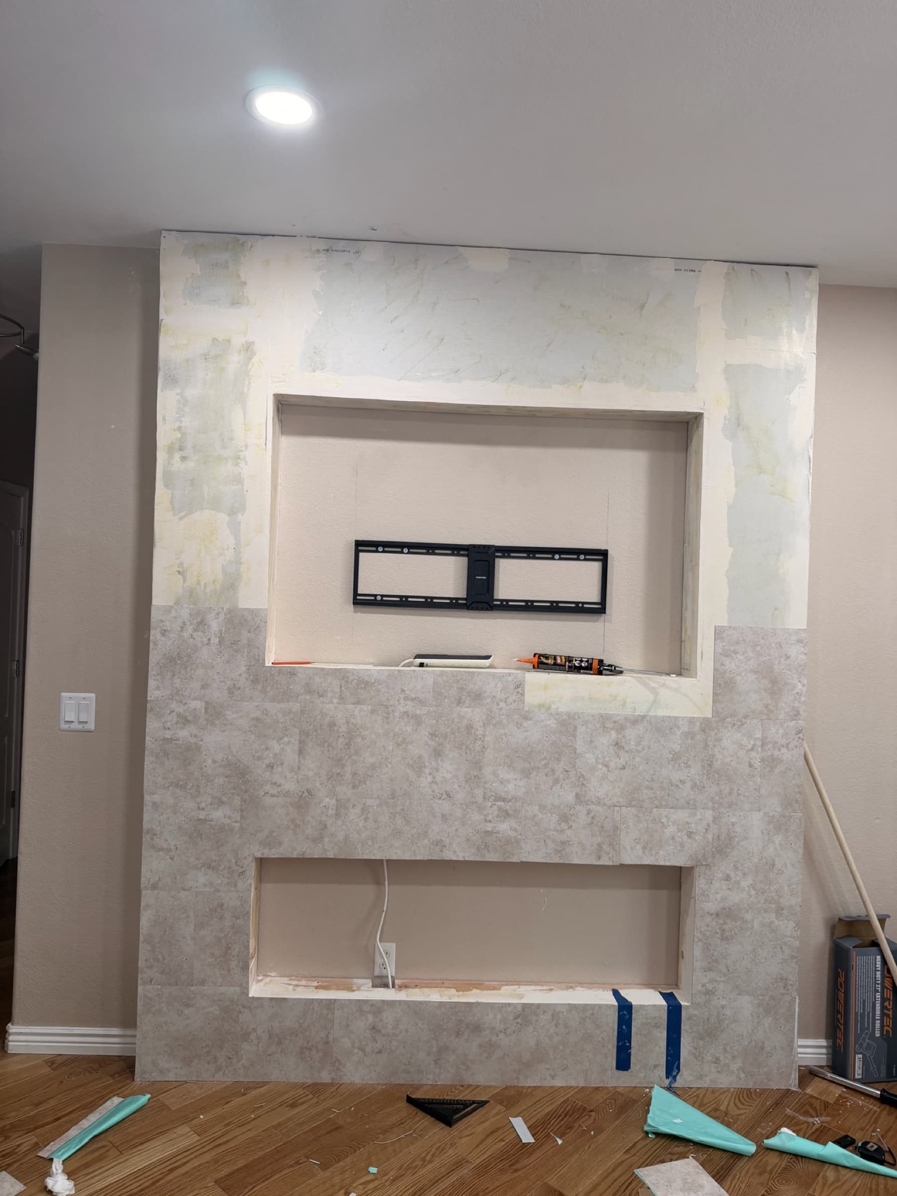 Stone tile installation in progress on a custom media wall built by Black Swan Repairs